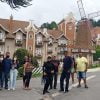 Grupo de turistas posando em frente a um edifício de estilo europeu com moinho de vento em Campos do Jordão