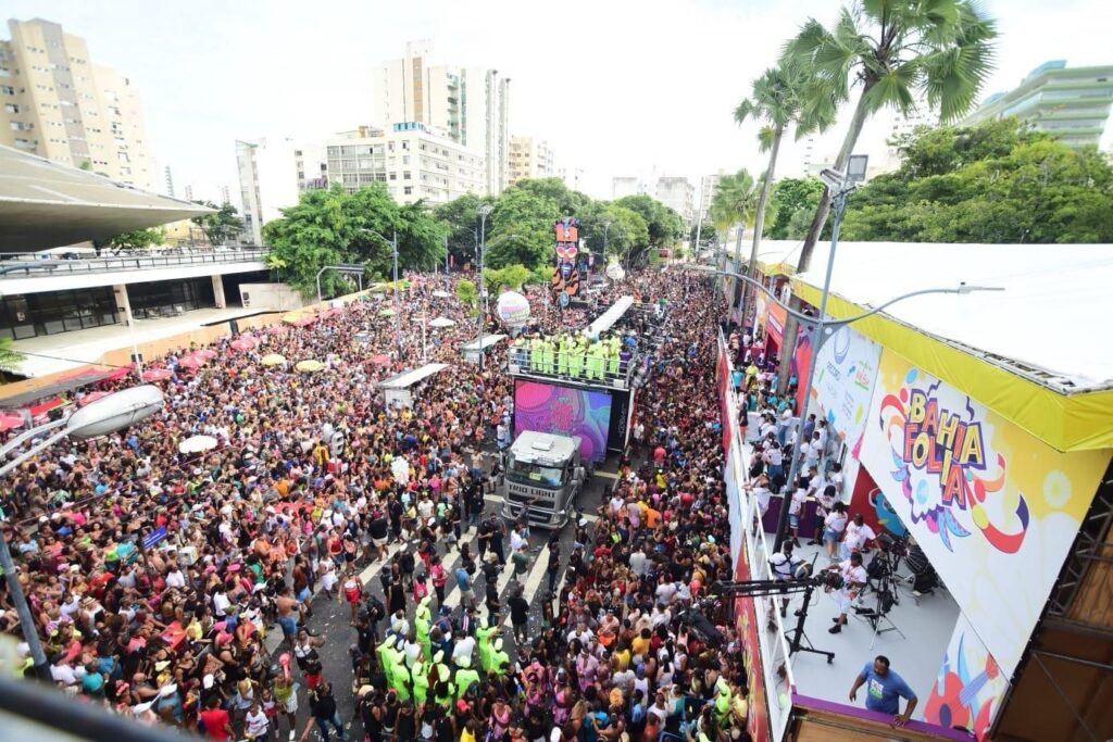 Imagem aérea do Carnaval de Salvador no Circuito Osmar (Campo Grande), com milhares de foliões nas ruas acompanhando um trio elétrico em meio à festa.